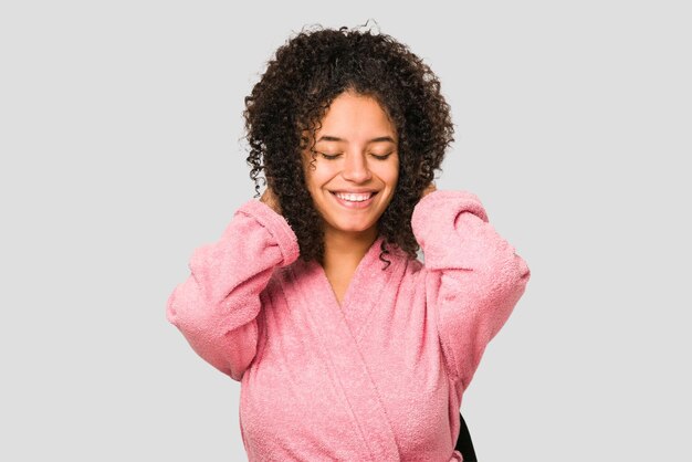 Jeune femme bouclée afro-américaine portant un peignoir rose isolé