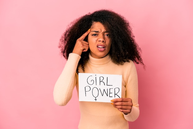 Jeune femme bouclée afro-américaine tenant un message de puissance de fille sur une pancarte montrant un geste de déception avec l'index.