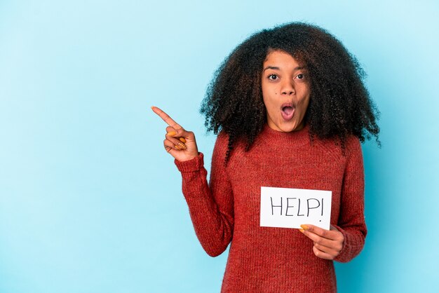 Jeune femme bouclée afro-américaine tenant une pancarte d'aide pointant vers le côté