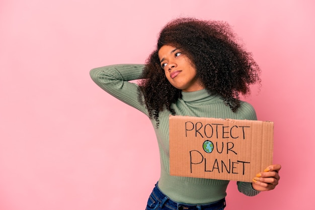 Jeune femme bouclée afro-américaine touchant l'arrière de la tête, pensant et faisant un choix.