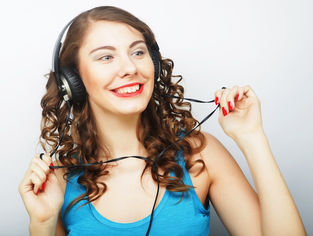 Jeune femme bouclée avec un casque écoutant de la musique. Prise de vue en studio.