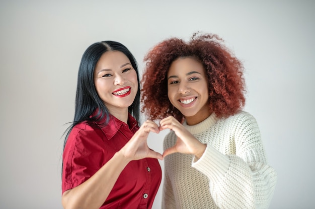 Photo jeune femme bouclée avec son joyeux ami asiatique