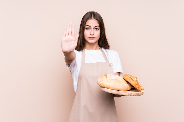 Jeune femme de boulanger caucasien isolé debout avec la main tendue montrant le panneau d'arrêt, vous empêchant.