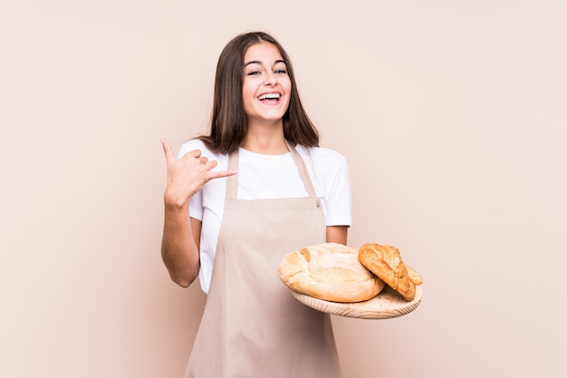 Jeune femme de boulanger caucasienne isolée montrant un geste d'appel de téléphone mobile avec les doigts.