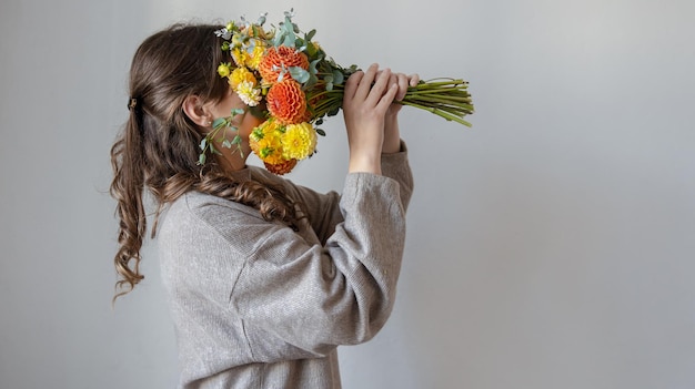 Jeune femme avec un bouquet de chrysanthèmes frais sur fond gris