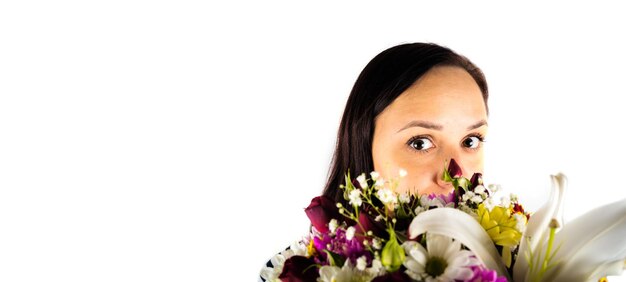 Jeune femme avec bouquet coloré de fleurs diverses sur fond blanc isolé Brunette regarde par derrière panier de fleurons