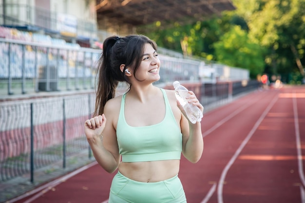 Une jeune femme avec une bouteille d'eau à l'entraînement au stade