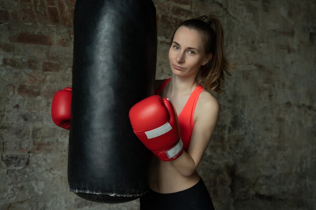 Jeune femme de boxeur athlétique à la salle de sport près de la poire de frappe