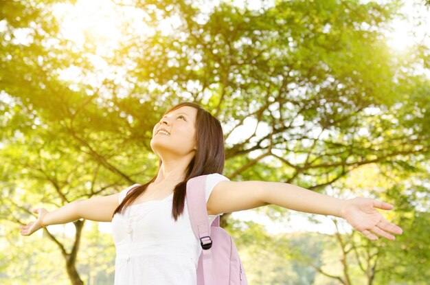 Une jeune femme avec les bras étendus debout près des arbres