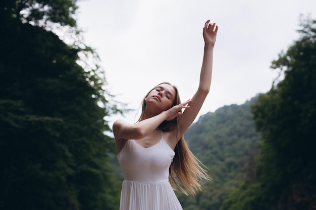 Jeune femme avec le bras levé debout contre les arbres