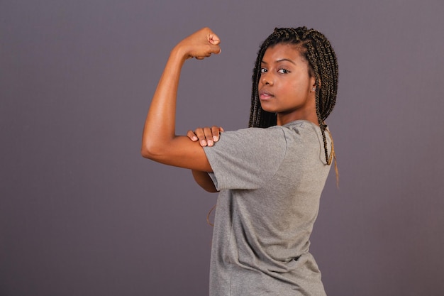 Jeune femme brésilienne afro montrant des biceps signe de force