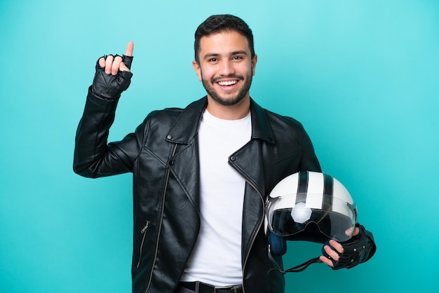 Jeune femme brésilienne avec un casque de moto isolé sur fond bleu pointant vers le haut une excellente idée