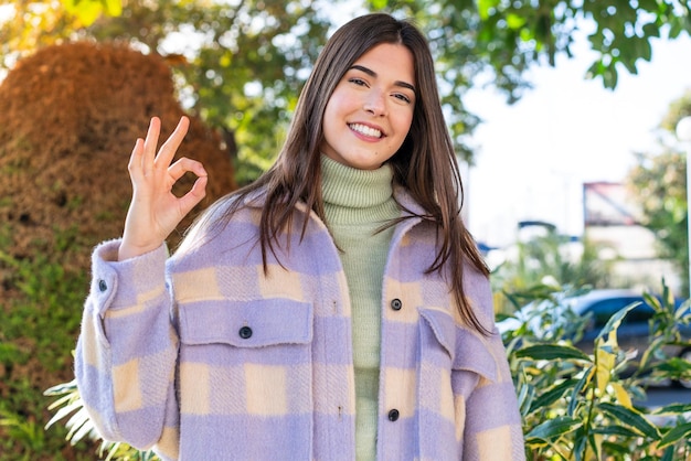 Jeune femme brésilienne dans un parc montrant un signe ok avec les doigts