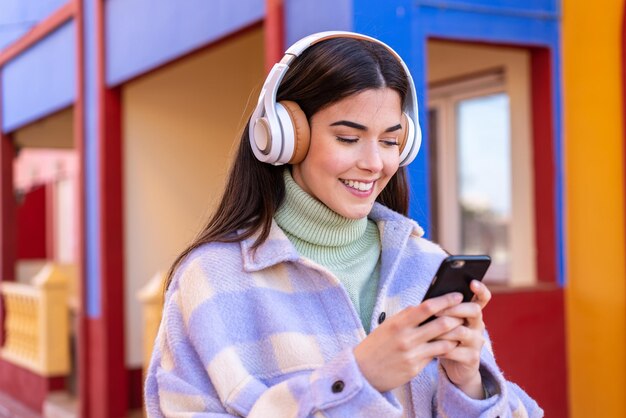 Jeune femme brésilienne à l'extérieur écoutant de la musique et regardant vers le mobile