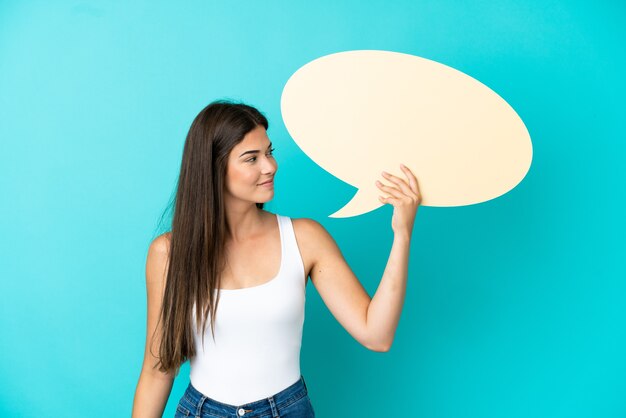 Jeune Femme Brésilienne Isolée Sur Fond Bleu Tenant Une Bulle De Dialogue Vide