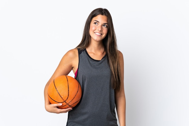 Jeune femme brésilienne jouant au basket-ball isolé sur un mur blanc en pensant à une idée tout en levant les yeux