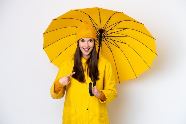 Jeune femme brésilienne avec manteau imperméable et parapluie isolé sur fond blanc avec une expression faciale surprise