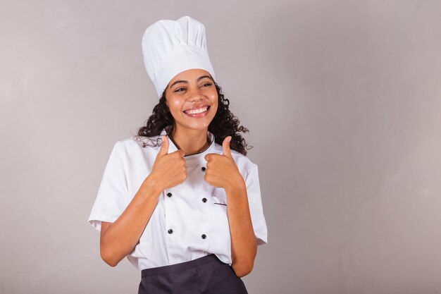 Jeune femme brésilienne noire cuisinier masterchef comme approbation des pouces de signe