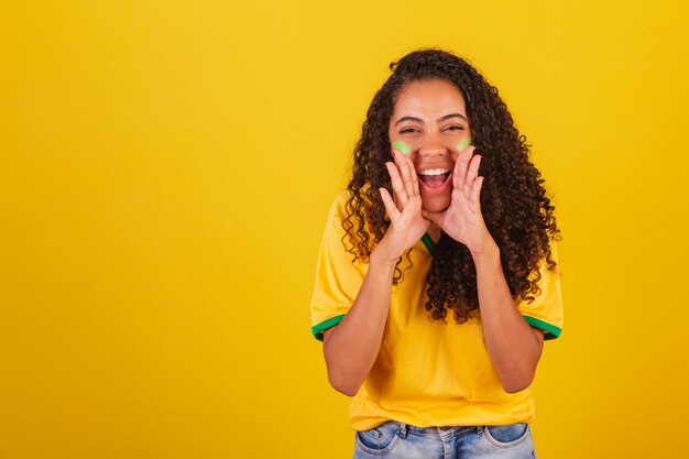 Jeune femme brésilienne noire fan de football hurlant de promotion