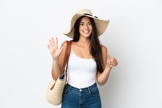 Jeune femme brésilienne avec Pamela tenant un sac de plage isolé sur fond blanc comptant six avec les doigts