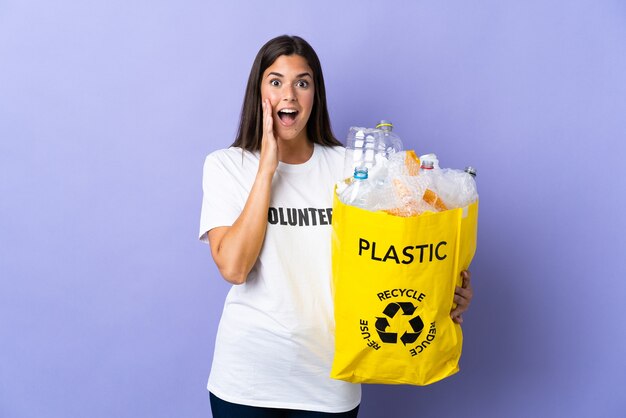Jeune femme brésilienne tenant un sac plein de bouteilles en plastique à recycler isolé