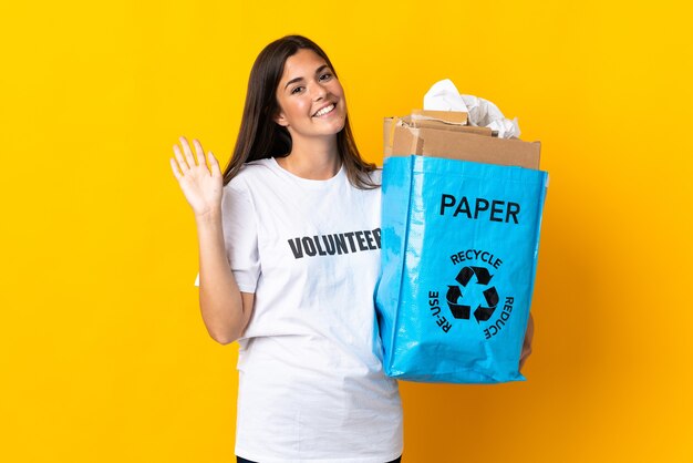 Jeune femme brésilienne tenant un sac de recyclage plein de papier à recycler isolé