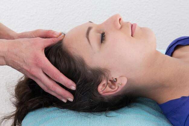 Jeune femme brillante recevant un massage de la tête dans un centre de spa