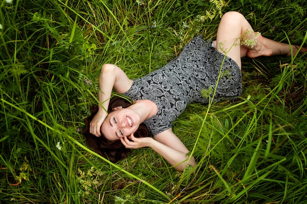 Jeune femme brune allongée sur l&#39;herbe verte.