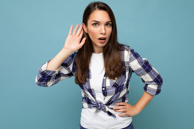 Jeune femme brune belle concentrée avec des émotions sincères portant chemise debout isolé sur bleu