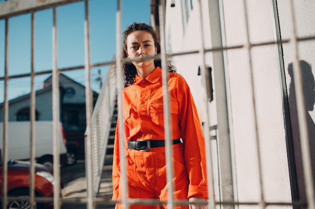 Jeune femme brune bouclée en costume orange Femme en portrait de salopette colorée