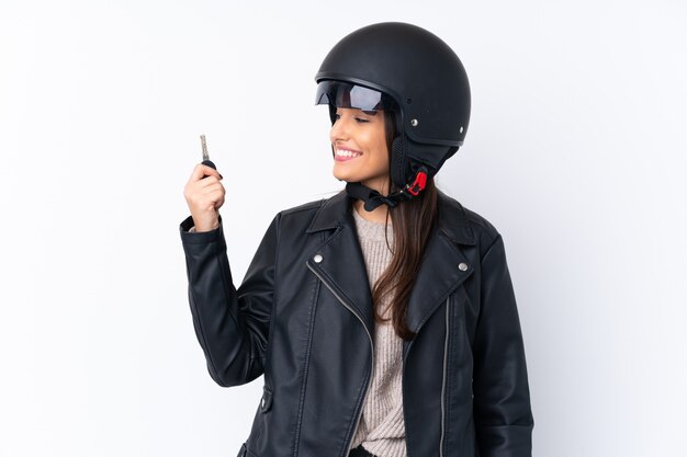 Jeune femme brune avec un casque de moto et tenant une clé sur blanc