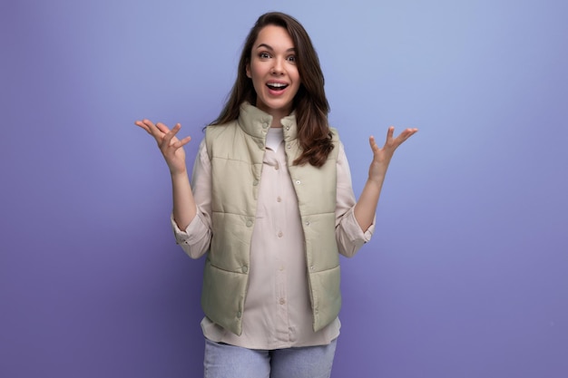 Une jeune femme brune caucasienne aux cheveux sous ses épaules sourit et pose sur le fond