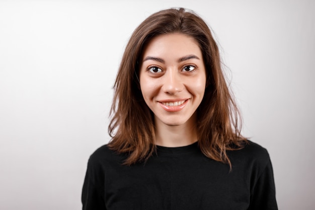 Jeune femme brune dans une chemise noire sur blanc.