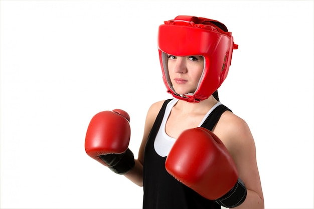 Jeune femme brune dans les gants de boxe rouges et un casque ayant un impact.