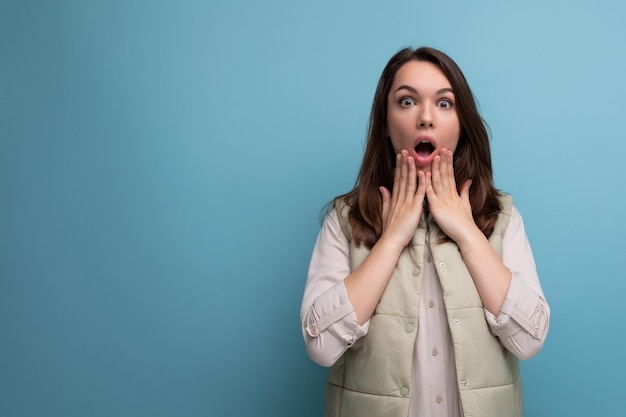 La jeune femme brune émotive montre la surprise avec des expressions faciales et des mains