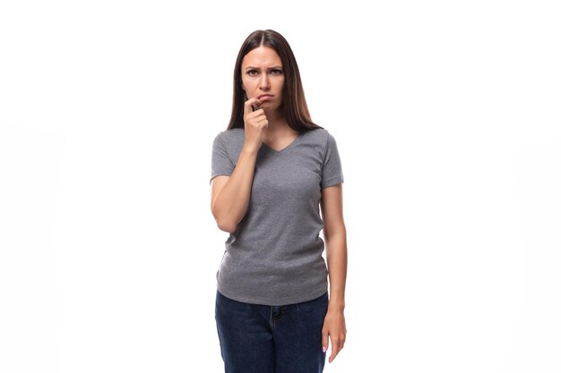 Jeune femme brune européenne surprise et bouleversée vêtue d'un t-shirt gris de base avec une maquette de marque