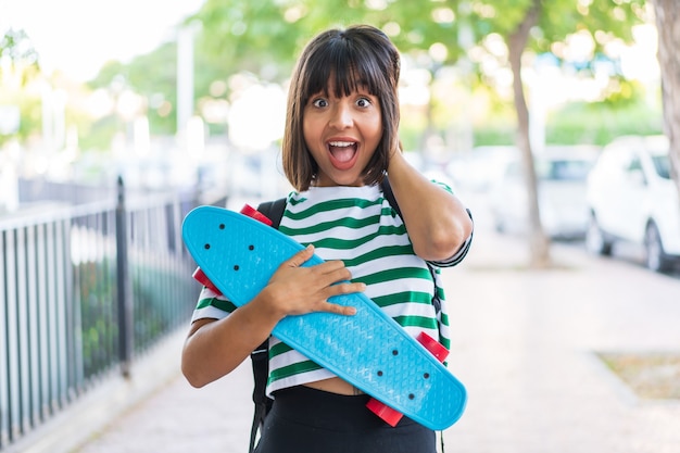 Jeune femme brune à l'extérieur avec un patin et faisant un geste de surprise