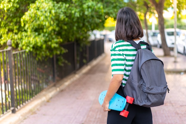 Jeune femme brune à l'extérieur avec un patin en position arrière