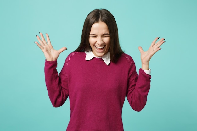 Photo jeune femme brune fille dans des vêtements décontractés posant les mains écartées isolées sur le portrait en studio de fond bleu vert turquoise mur. concept de style de vie des gens. maquette de l'espace de copie. regarder le sourire de la caméra