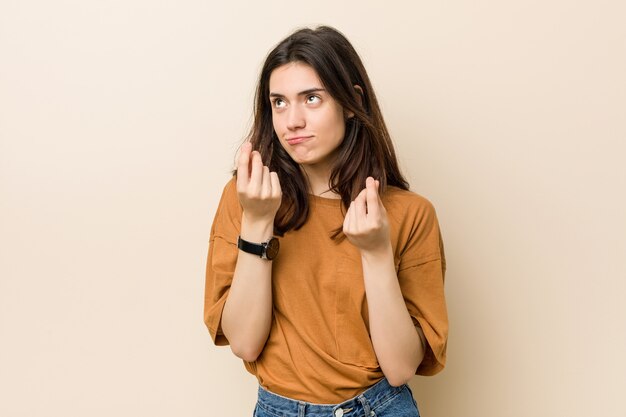 Jeune femme brune sur fond beige montrant qu'elle n'a pas d'argent