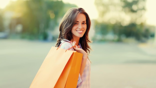une jeune femme brune heureuse avec des sacs d'achat qui se promène dans la ville