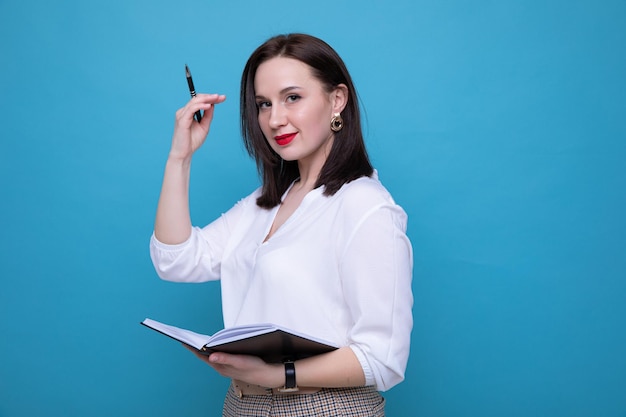 Jeune femme brune avec un journal et un stylo sur fond bleu