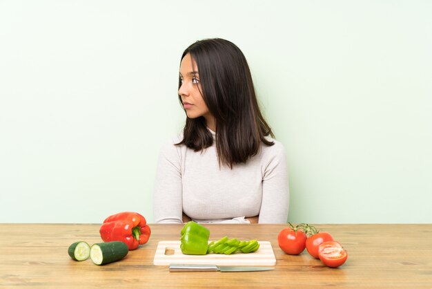 Jeune femme brune avec des légumes à la recherche de côté