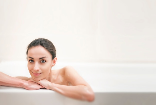 Jeune femme brune magnifique prend la procédure de bain à la maison