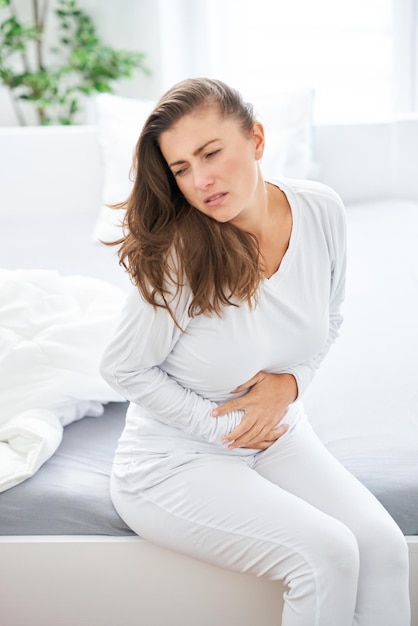 Jeune femme brune malade au lit