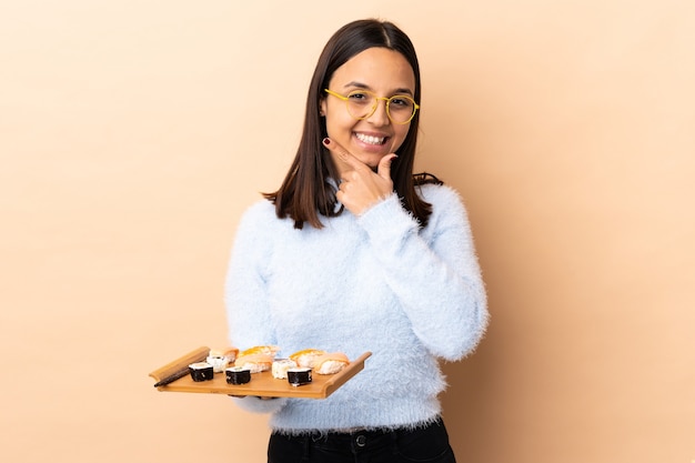 Jeune femme brune métisse tenant des sushis heureux et souriant