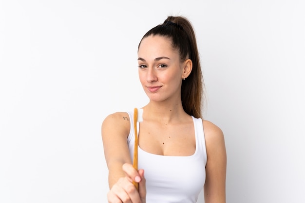 Jeune femme brune sur un mur blanc isolé avec une brosse à dents