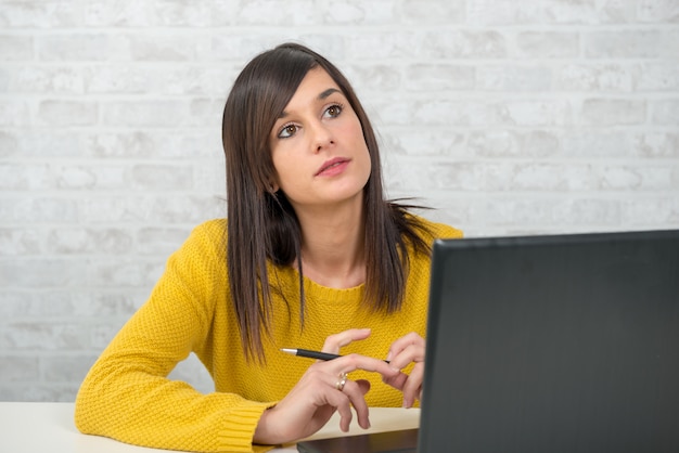 Jeune femme brune pensive au bureau