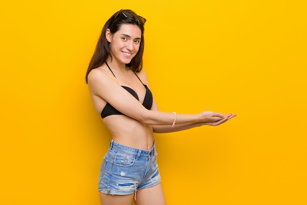 Jeune femme brune portant un bikini sur fond jaune