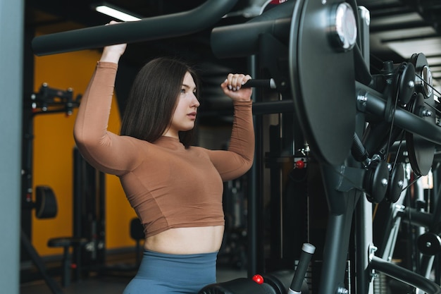 Jeune femme brune de remise en forme s'entraînant pour l'équipement des muscles du dos au gymnase